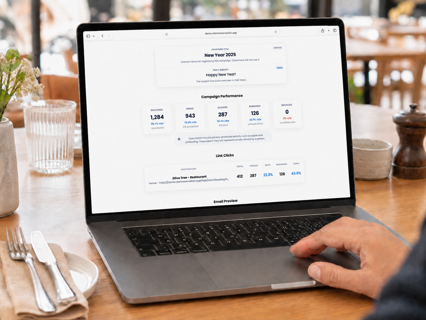 A hospitality professional reviewing high-performing Client Reservation email analytics on a MacBook