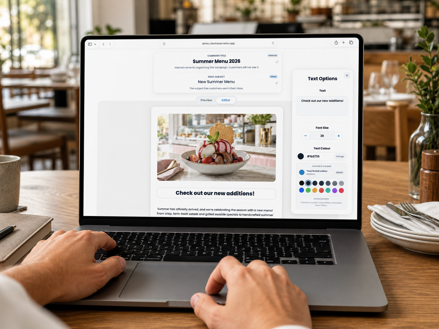 A hospitality manager designing a Client Reservation marketing email on a MacBook