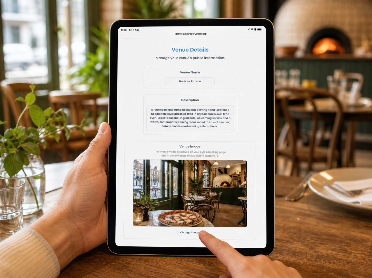 A person changing venue details on a portrait iPad in a modern pizza restaurant